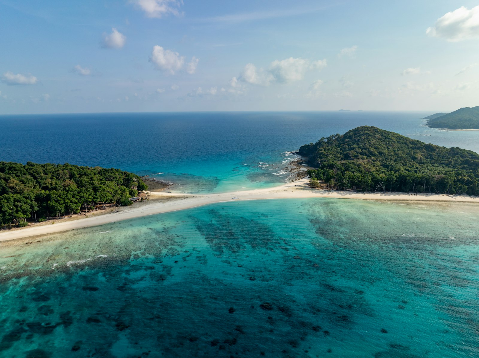 White sandbar separates turquoise and deep blue ocean waters.